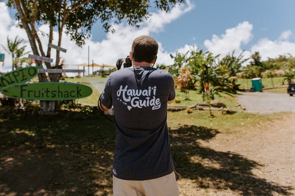 John photographing a roadside fruit stand in a Hawaii-Guide.com shirt