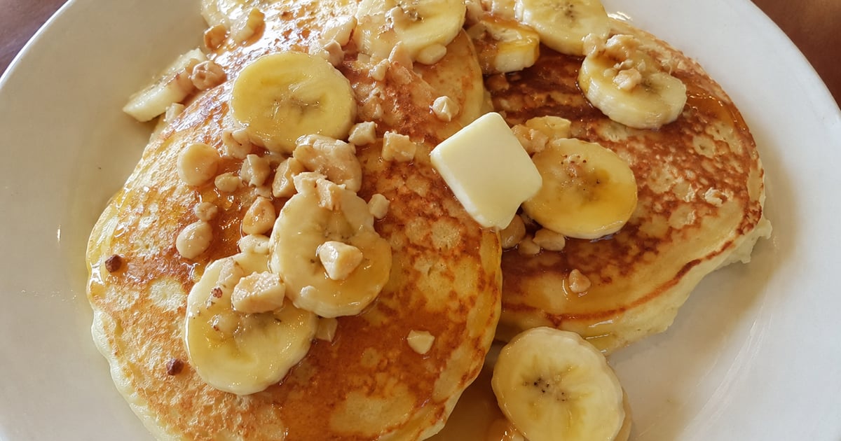 A stack of Hawaii banana macadamia nut pancakes with coconut syrup and toasted mac nuts