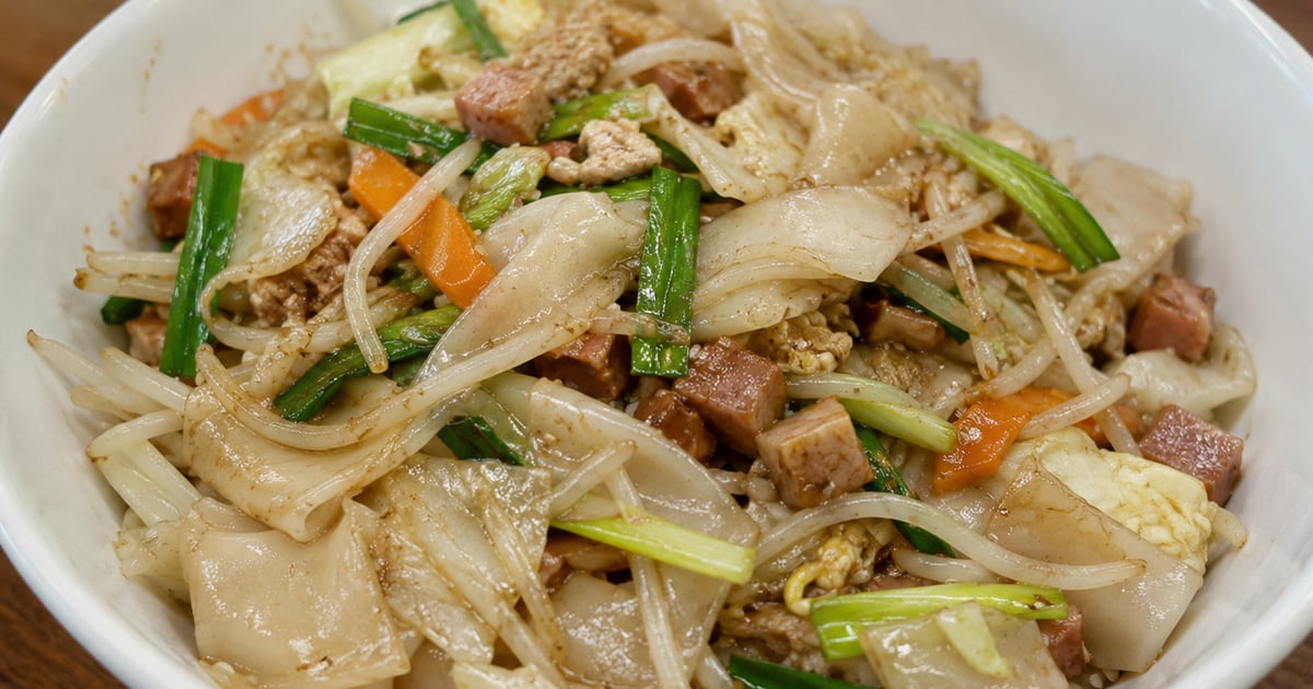 A plate of Hawaiian chow fun — wide rice noodles with char siu pork, bean sprouts, and green onion