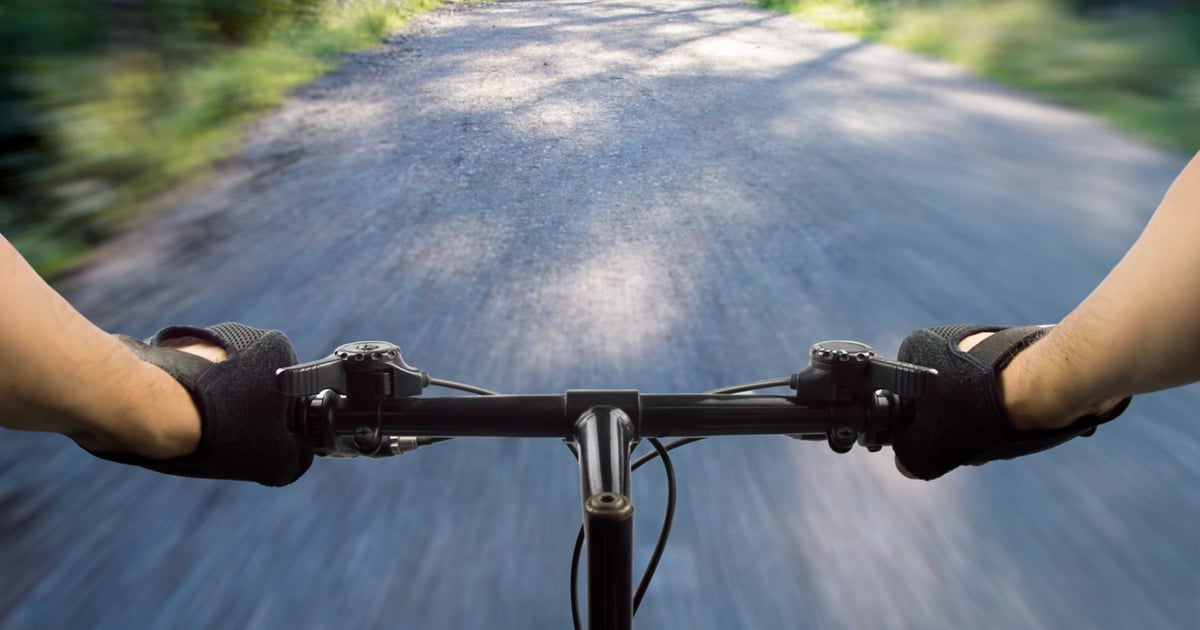 Cyclist's view over mountain bike handlebars on a forest road