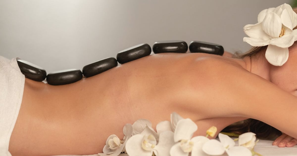 Spa guest resting with warm stones and white flowers during a treatment