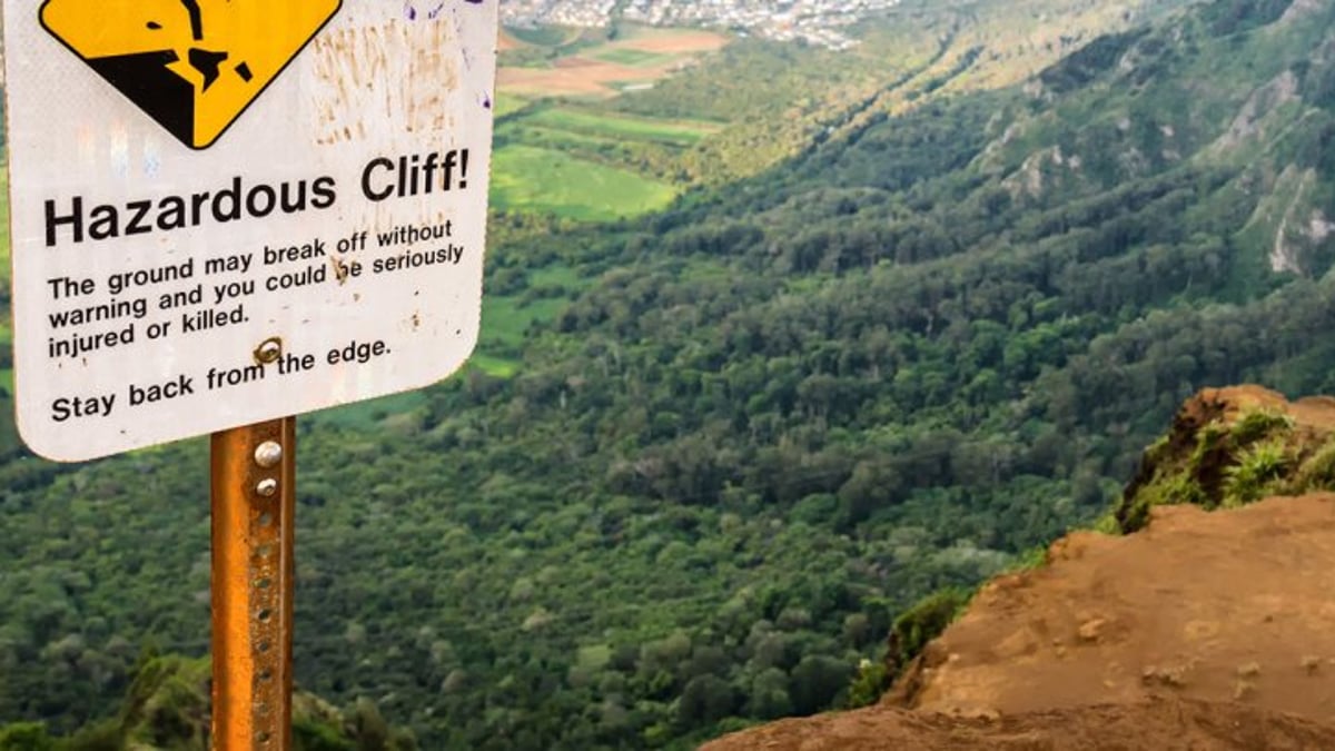Hazardous cliff warning beside a steep green Hawaii valley
