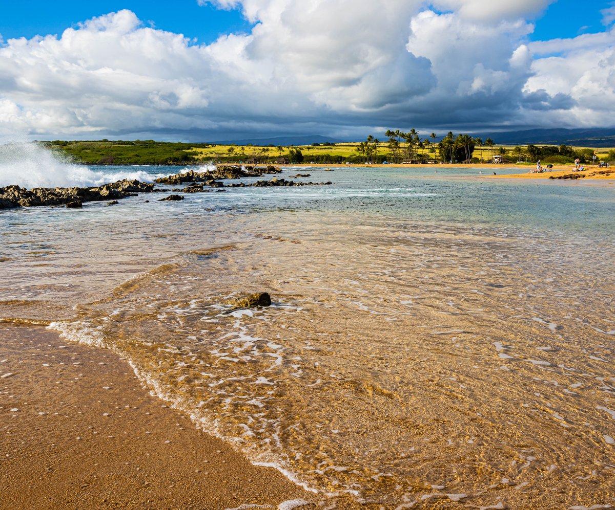 Salt Pond Beach on Kauai with shallow water, clouds, and a broad sandy shoreline.
