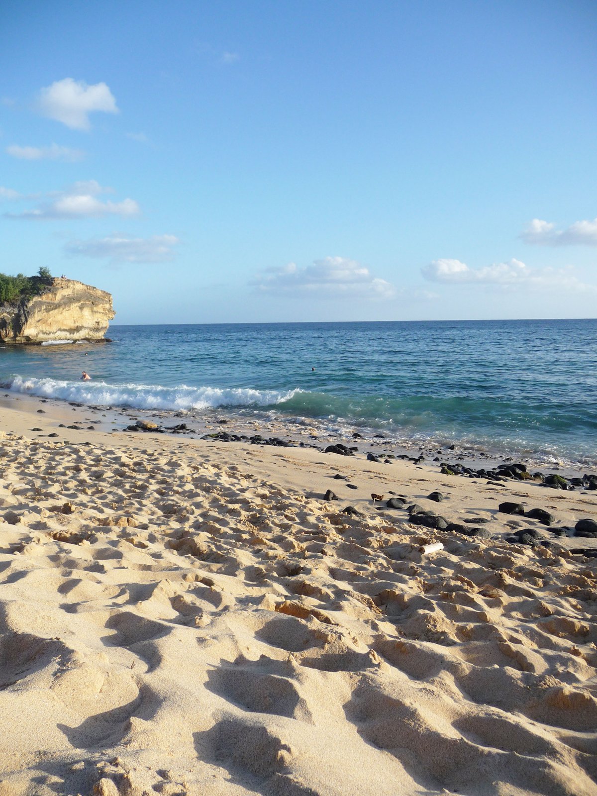 Shipwreck Beach on Kauaʻi's south shore, framed by lithified sandstone cliffs and driftwood scattered along the tideline.