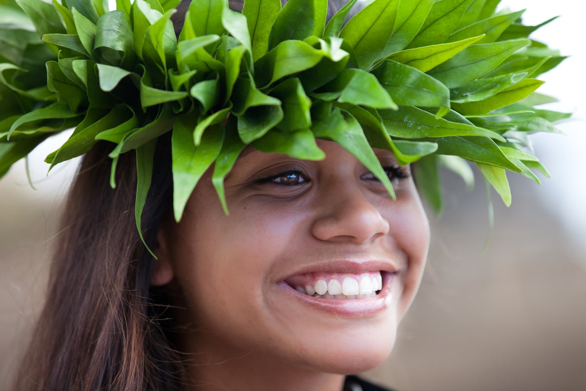 Young Hawaiian woman in a haku lei head wreath smiling at the camera