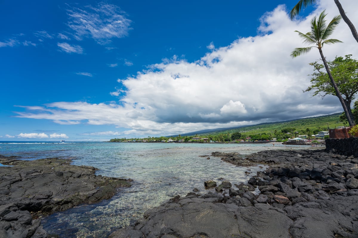 Snorkelers wading into the shallow inner reef at Kahaluʻu Beach Park on the Big Island of Hawaiʻi.