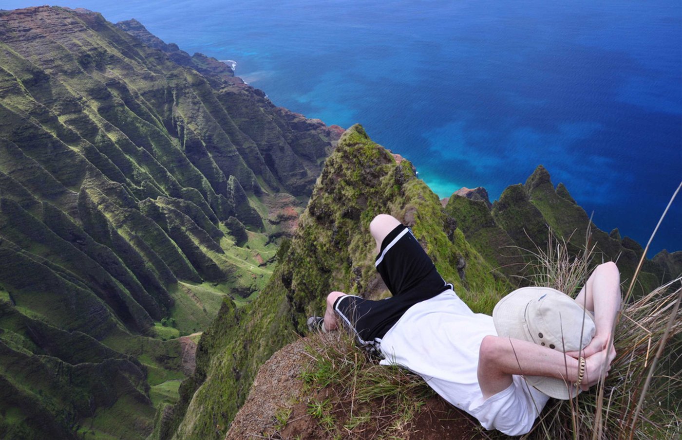 John lying on a narrow Kalalau area ridgeline above the Na Pali Coast during a 2011 guided hike