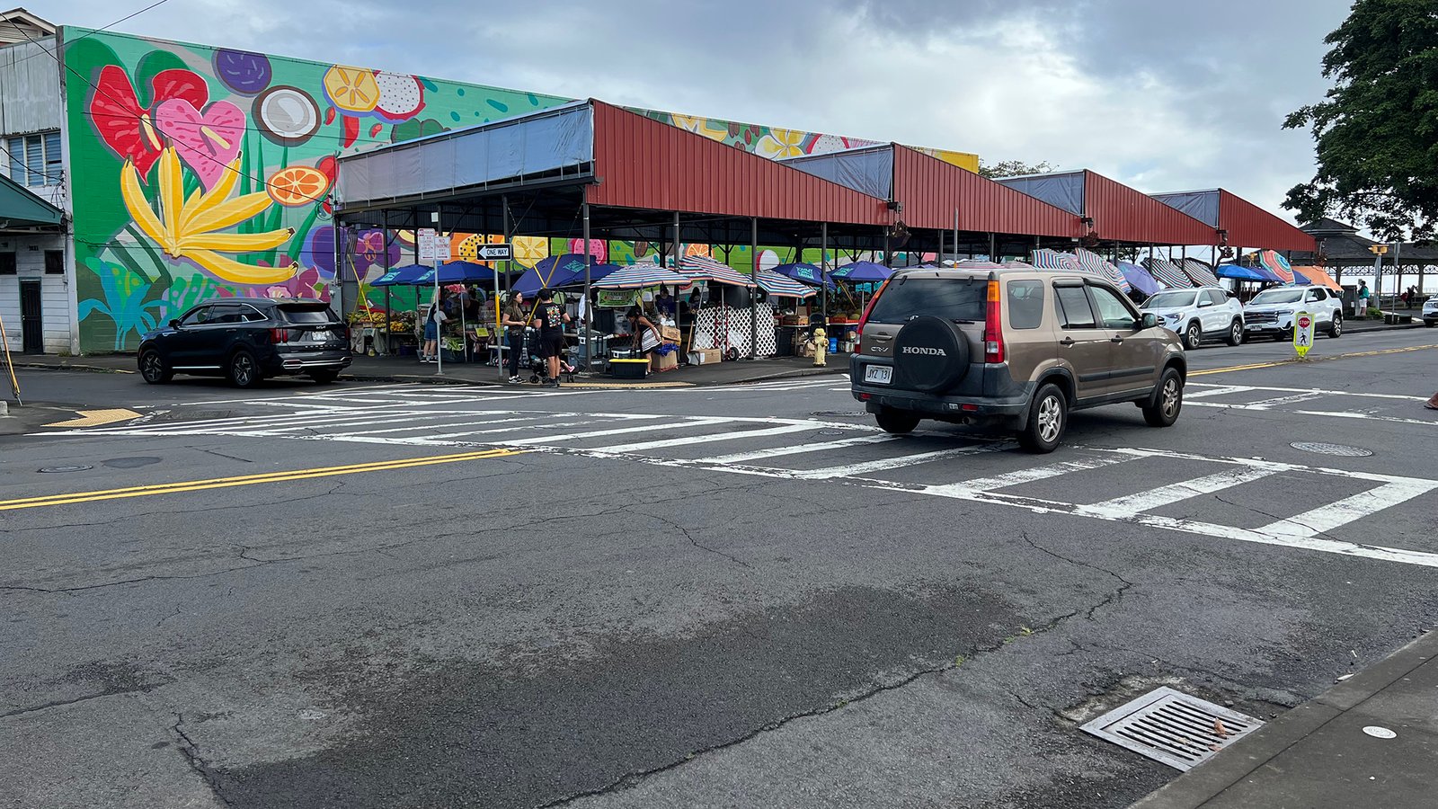 Hilo Farmers Market on the Big Island, with shoppers under colorful awnings beside a painted market building
