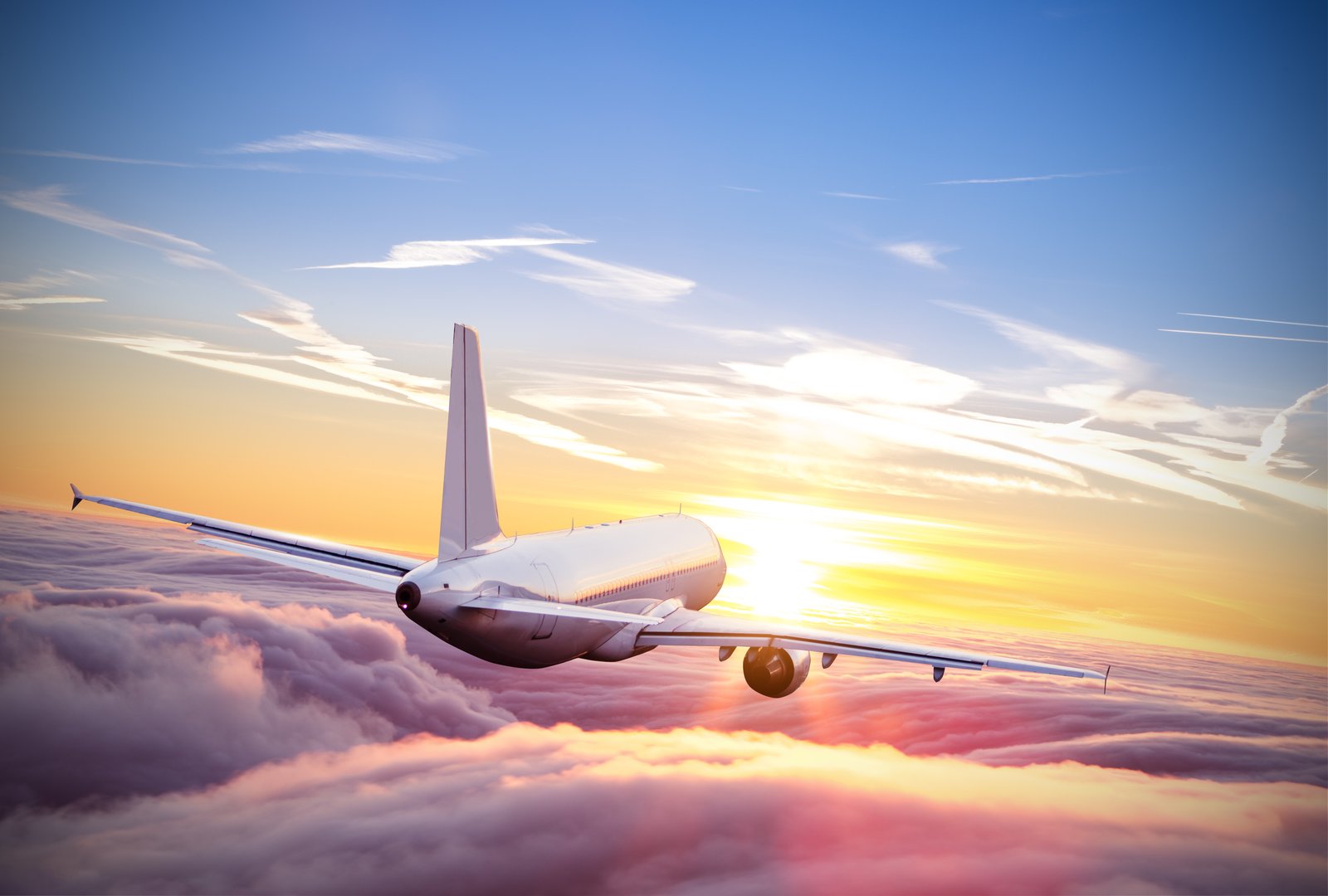 A passenger jet flying above the clouds at sunset