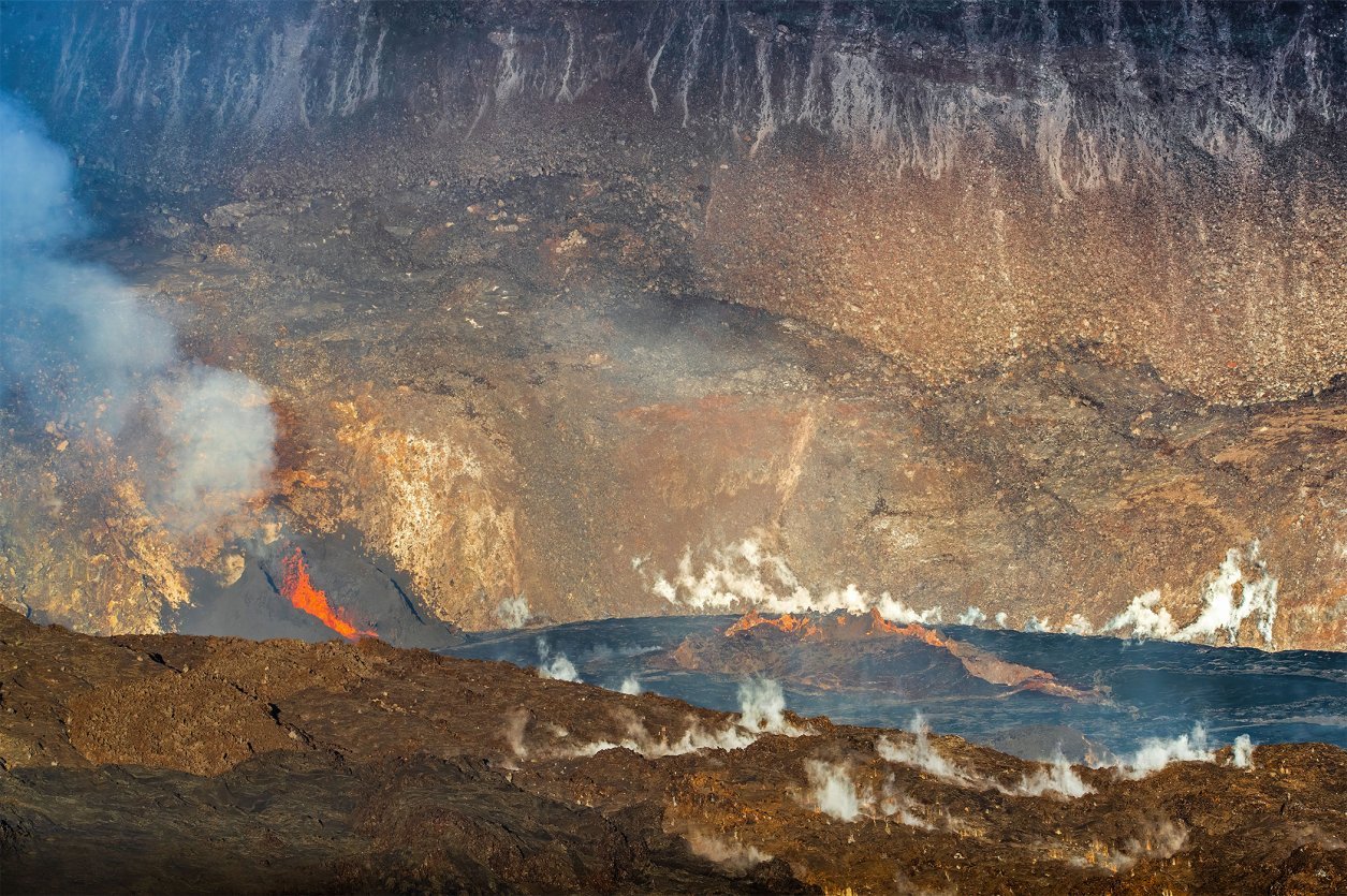 Nighttime view of Kīlauea's Halemaʻumaʻu crater lit orange by lava fountains, seen from the Keanakākoʻi Overlook inside Hawaiʻi Volcanoes National Park.