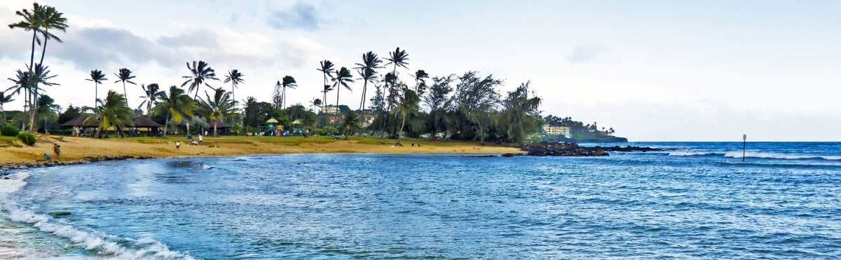 Families and beachgoers at Poipu Beach on Kauai, one of Hawaii's best family beaches.