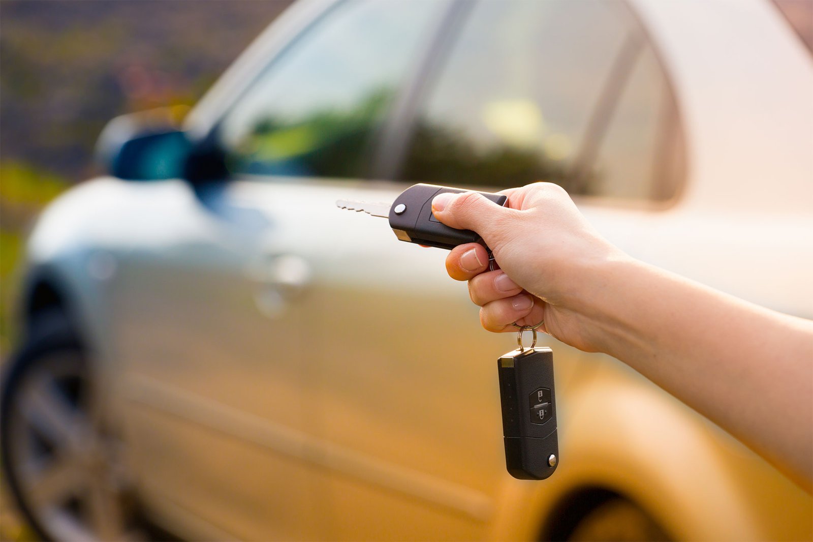Traveler holding a rental-car key beside a parked vehicle.