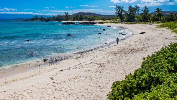 Tori walking alone across Makalawena Beach on the Big Island