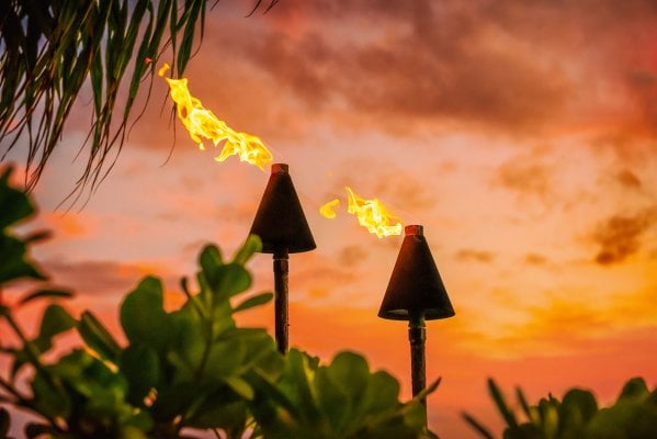 Tiki torches against a sunset sky at a Hawaii luau