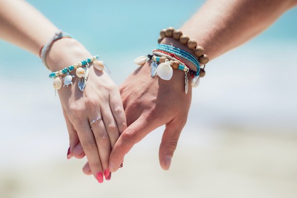 People holding hands with jewelry on that is also a type of souvenir to get from Hawaii