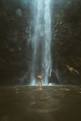 Person swimming in water fed by a waterfall while on an adventure in Maui Hawaii