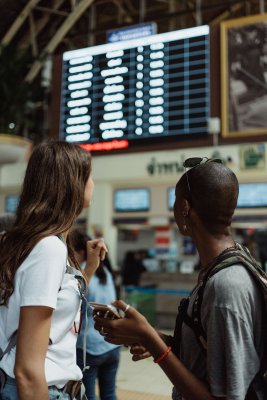 Two people looking toward the flight board in an airport as they arrived early. 