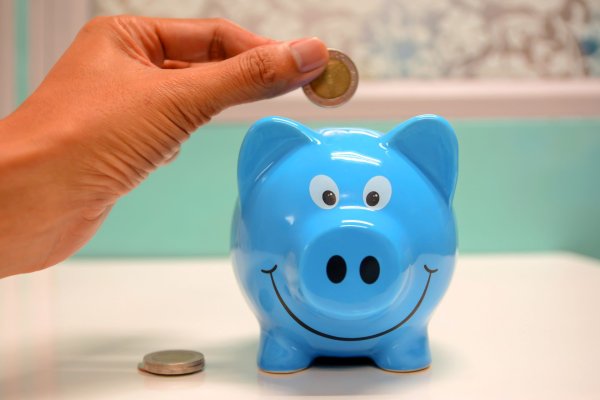 A blue piggy bank with a coin going in to represent saving money by choosing free and easy relaxing activities to do in Oahu