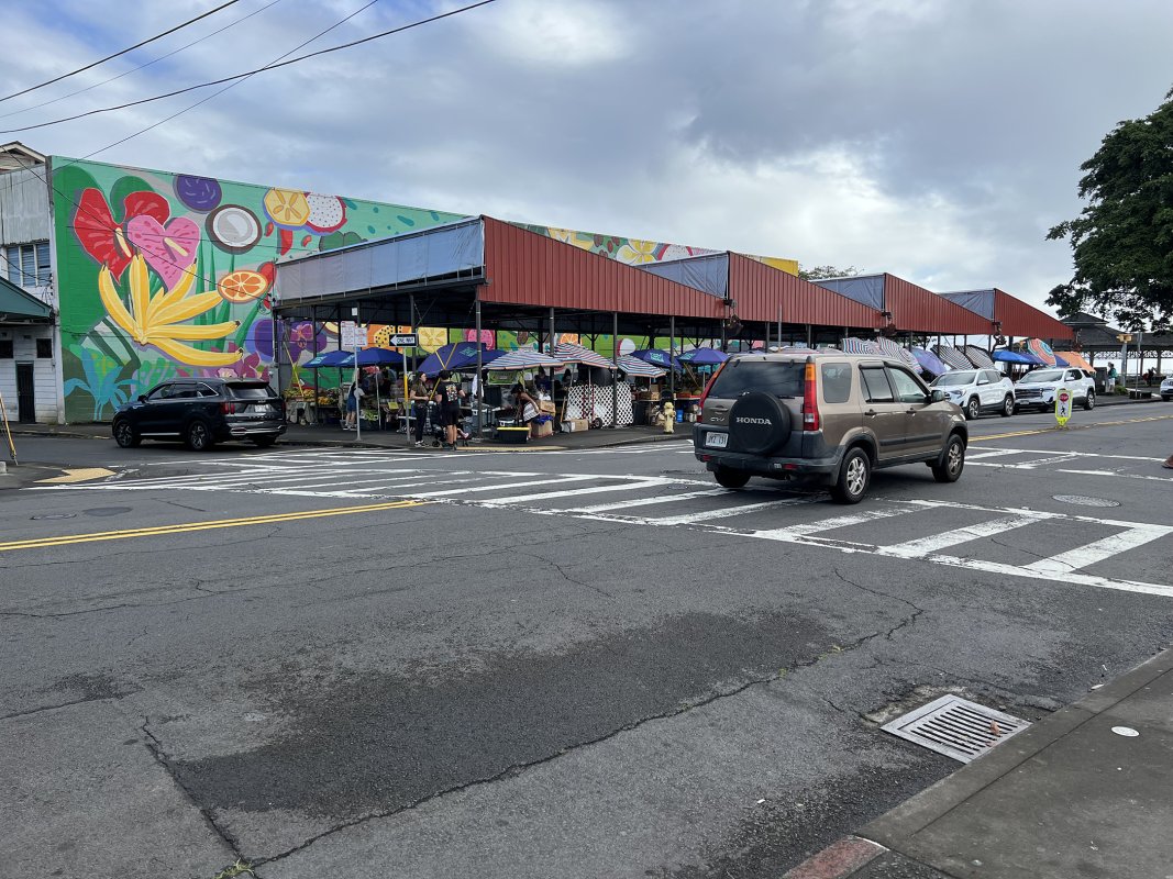 Colorful mural, market stalls, and cars outside Hilo Farmers Market