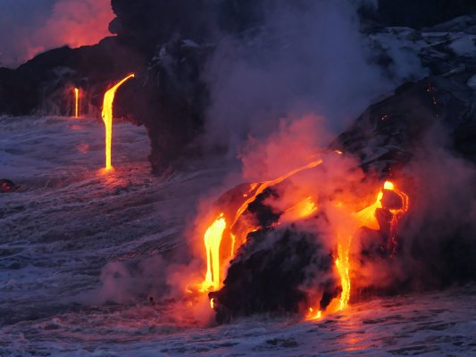 Lava flowing off of igneous rocks at night in the park.