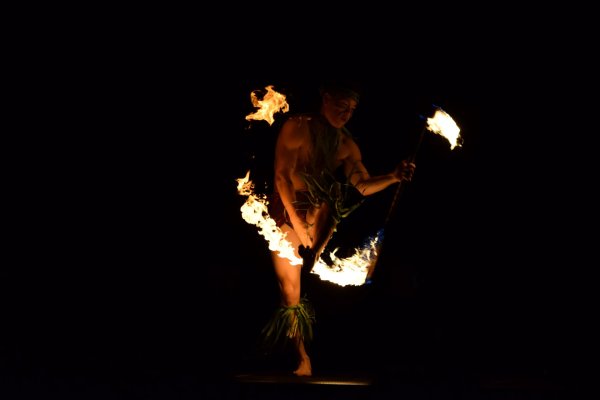 A man spinning fire at a sunset Luau in Maui