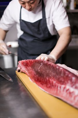 A person cutting fish meat on a cutting board in a kitchen after going on a fishing activity. 