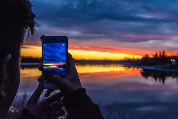 A person using their phone to take a photo to represent taking lots of photos of activities and sights as a good idea when you're in Honolulu Hawaii for 48 hours