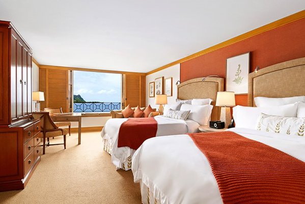 A fresh, clean and spacious luxury hotel room with two beds overlooking the water outside of 1 Hotel Hanalei Bay in Kauai.