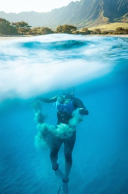 Woman rock diving and coming up from the bottom while still submerged in water
