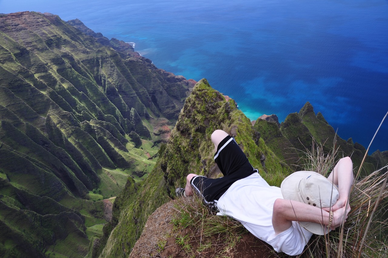 Hiker at the cliff edge above the Nā Pali Coast, Kauaʻi